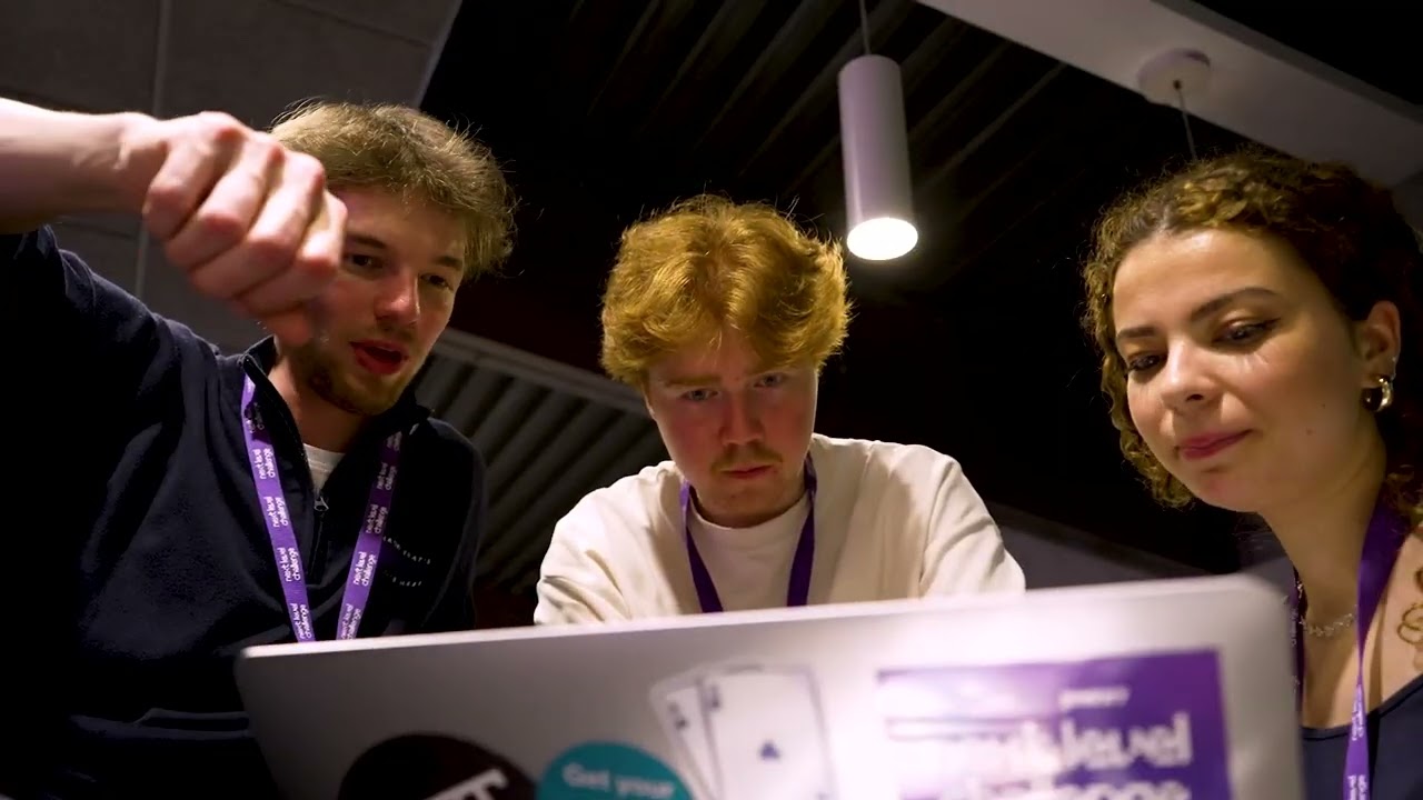 Three participants working together on a laptop during the hackathon